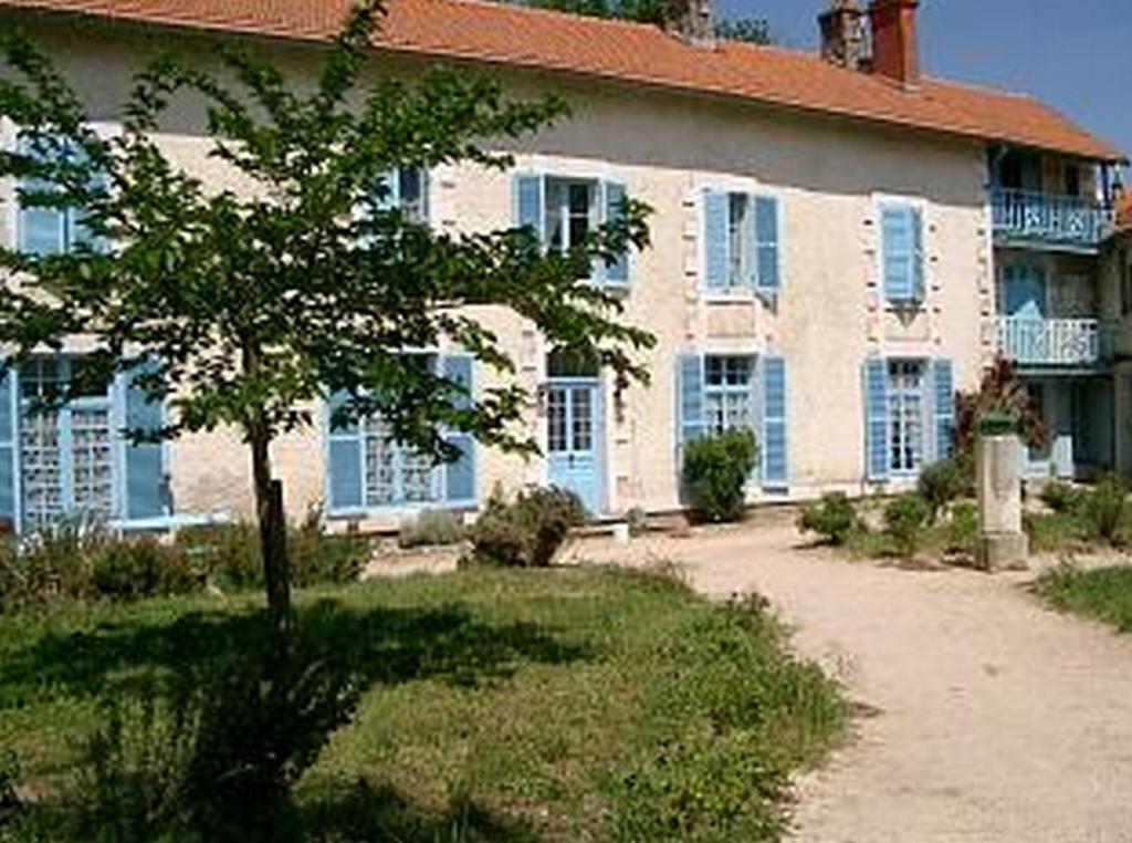 une grande maison avec un arbre en face dans l'établissement La Ferme Antoinette, aux Mathes