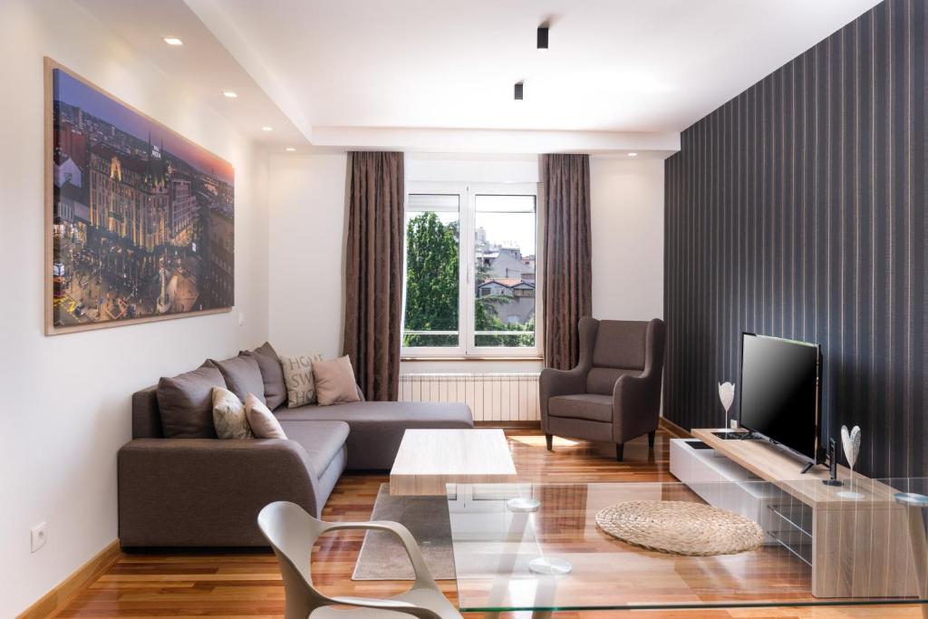 Apartments Feel Belgrade في بلغراد: غرفة معيشة مع أريكة وتلفزيون