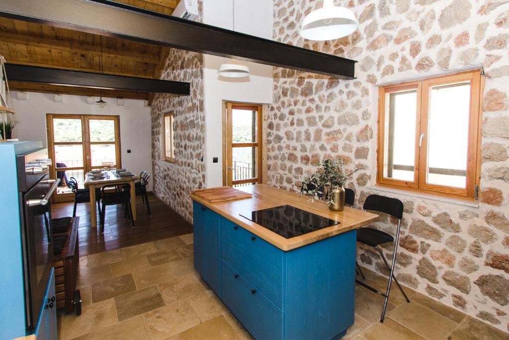 a kitchen with a blue island in a stone wall at Apartment Komoda in Kaprije