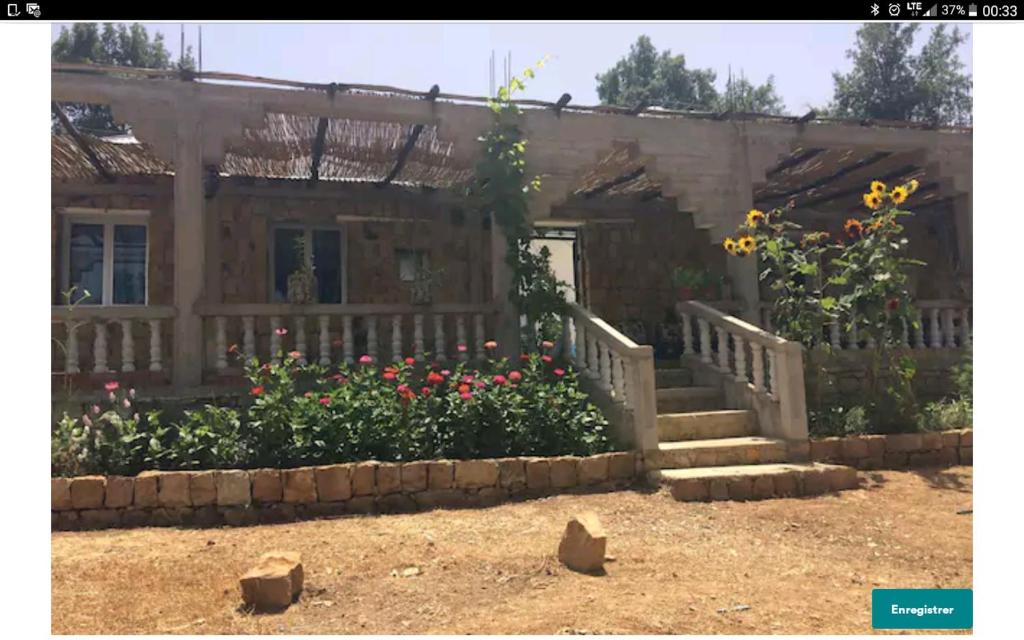 Una casa con flores y escaleras delante. en Maison d'hôtes "Abou-Hachem" en Melaah