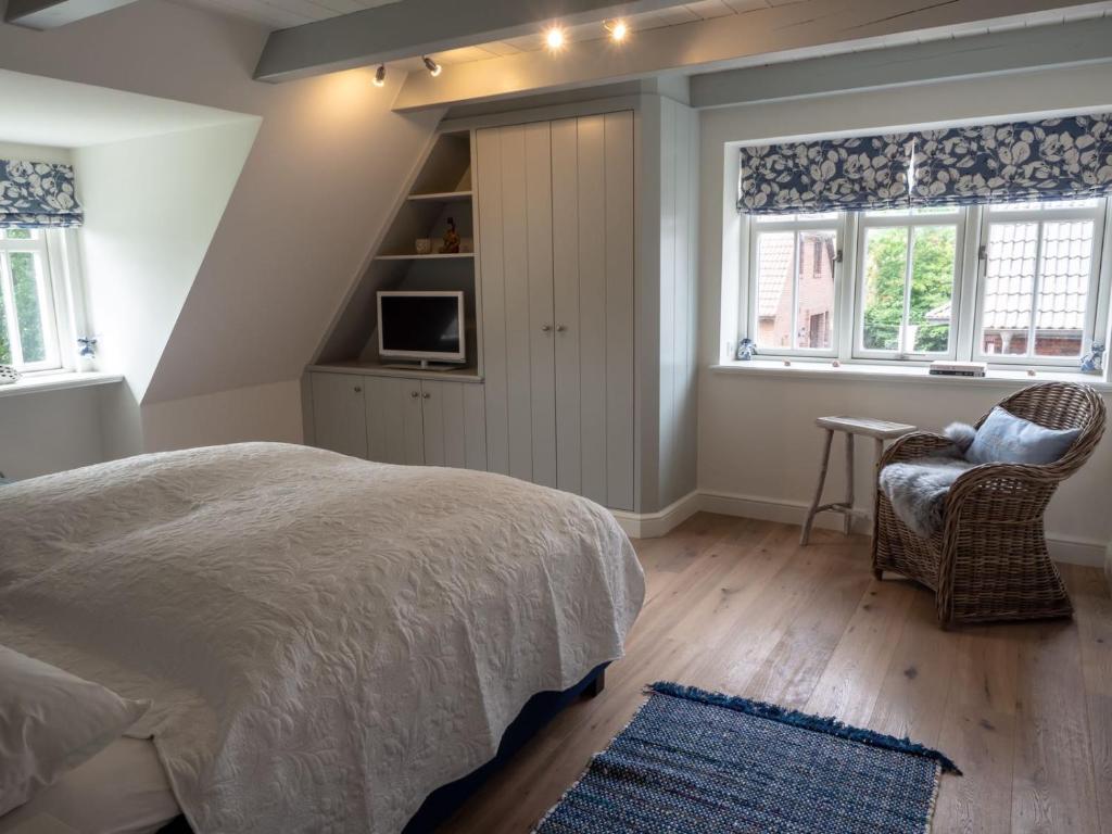 a bedroom with a bed and a chair and windows at Hygge Hus in Westerland