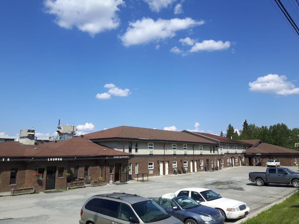 un parking avec des voitures garées devant un bâtiment dans l'établissement Prospector Inn, à Creighton