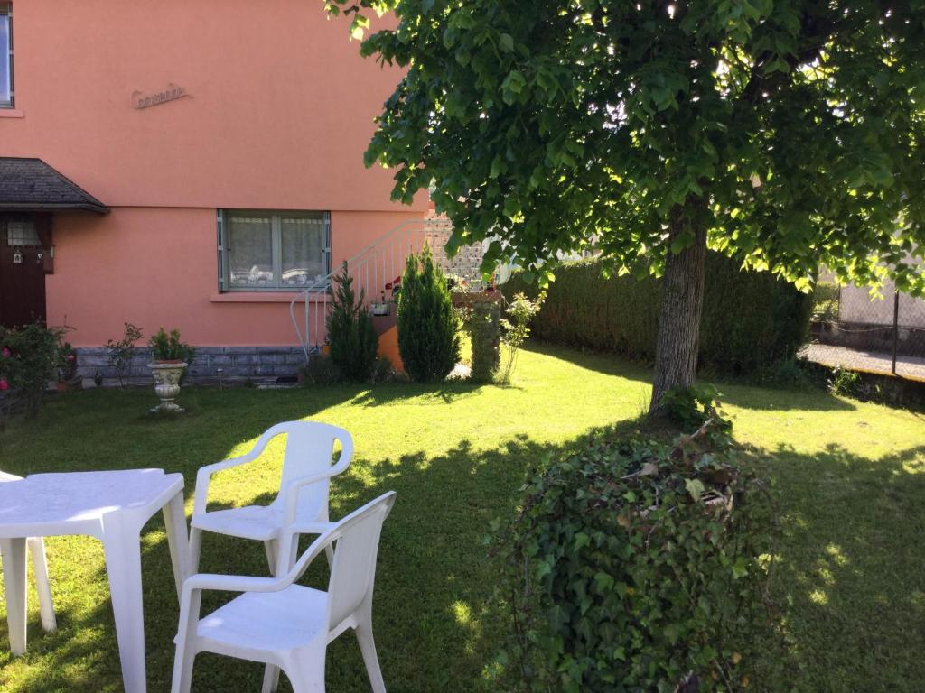two white chairs and a table under a tree at Appartement indépendant dans Villa Corisande in Bagnères-de-Bigorre
