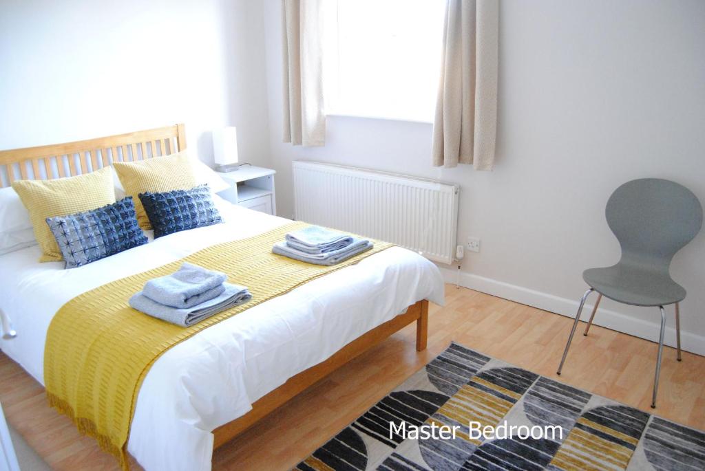 a bedroom with a bed with a yellow blanket and a chair at Ash House in Uppingham