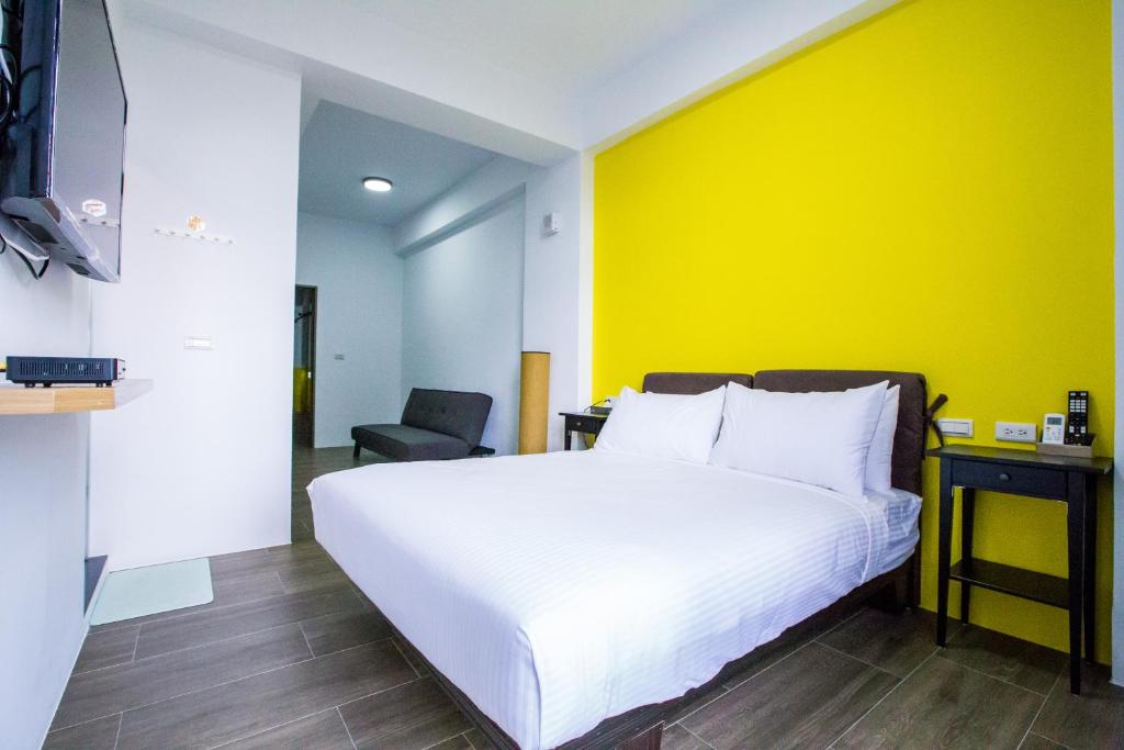 a bedroom with a white bed and a yellow wall at Central Woods in Yilan City