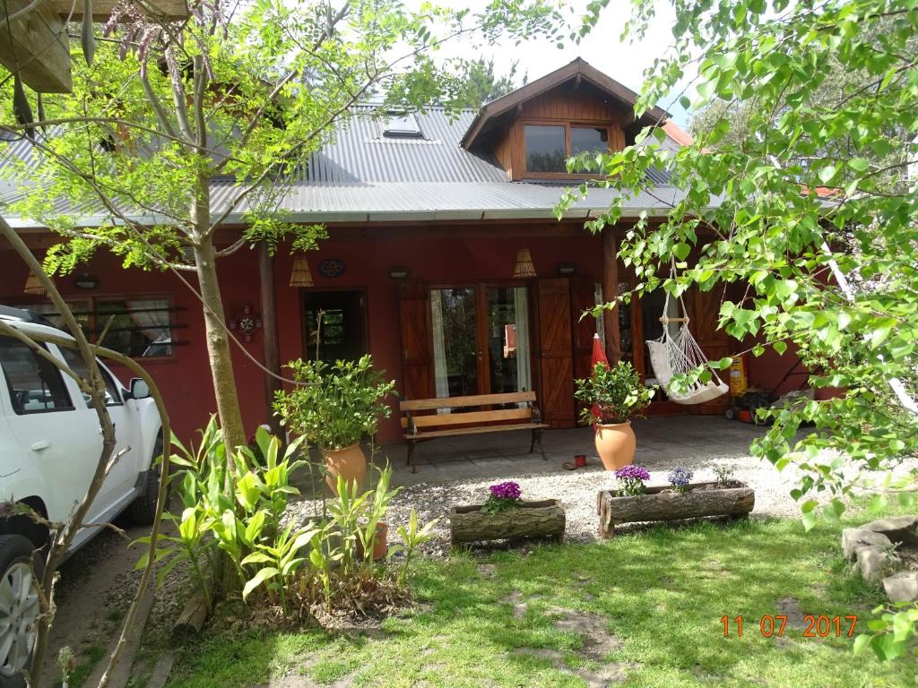 una pequeña casa roja con porche y algunas plantas en CABAÑA EN MIRAMAR en Miramar
