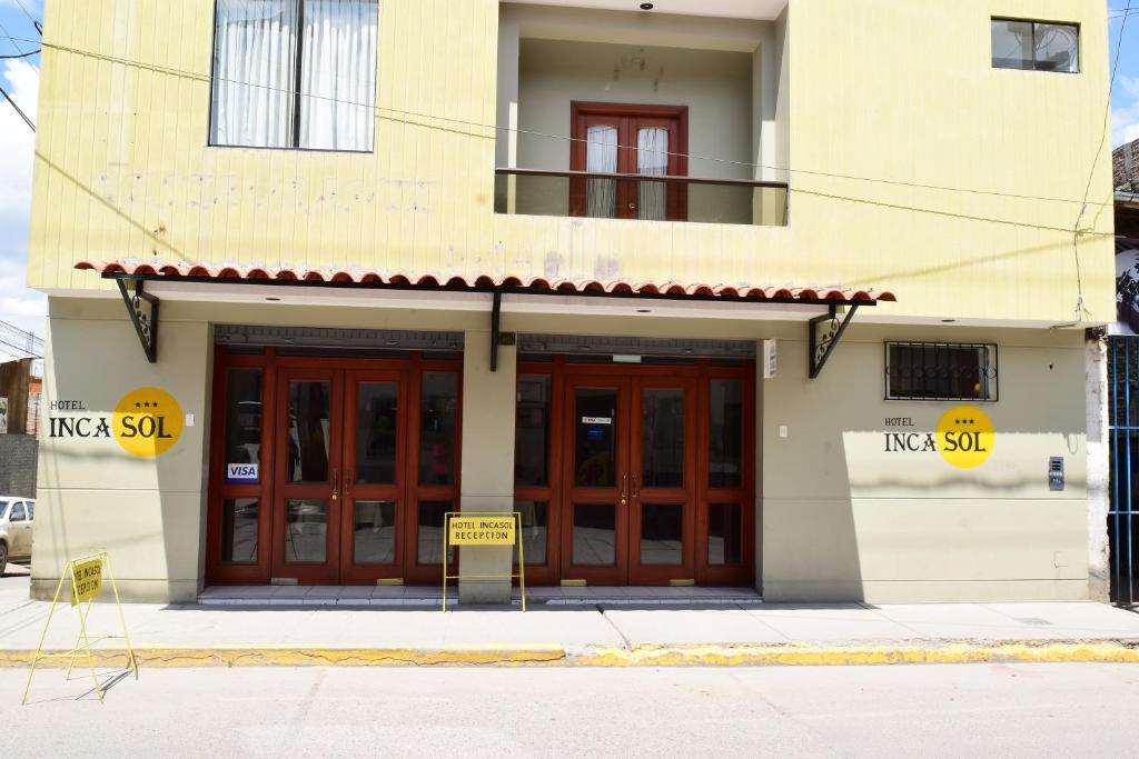 un edificio con puertas rojas y un cartel delante de él en Hotel Incasol, en Ayacucho