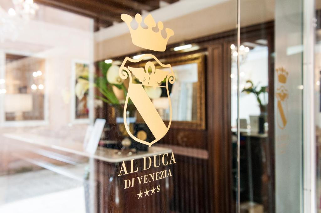 un cartel en una puerta de cristal con una corona de oro. en Hotel Al Duca Di Venezia, en Venecia