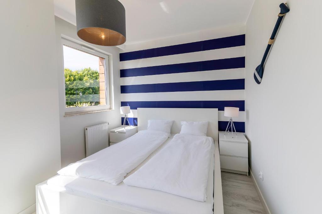 ヤストシェンビャ・グラにあるTriApart Kuracyjnaの青と白のストライプを用いた客室の白いベッド1台