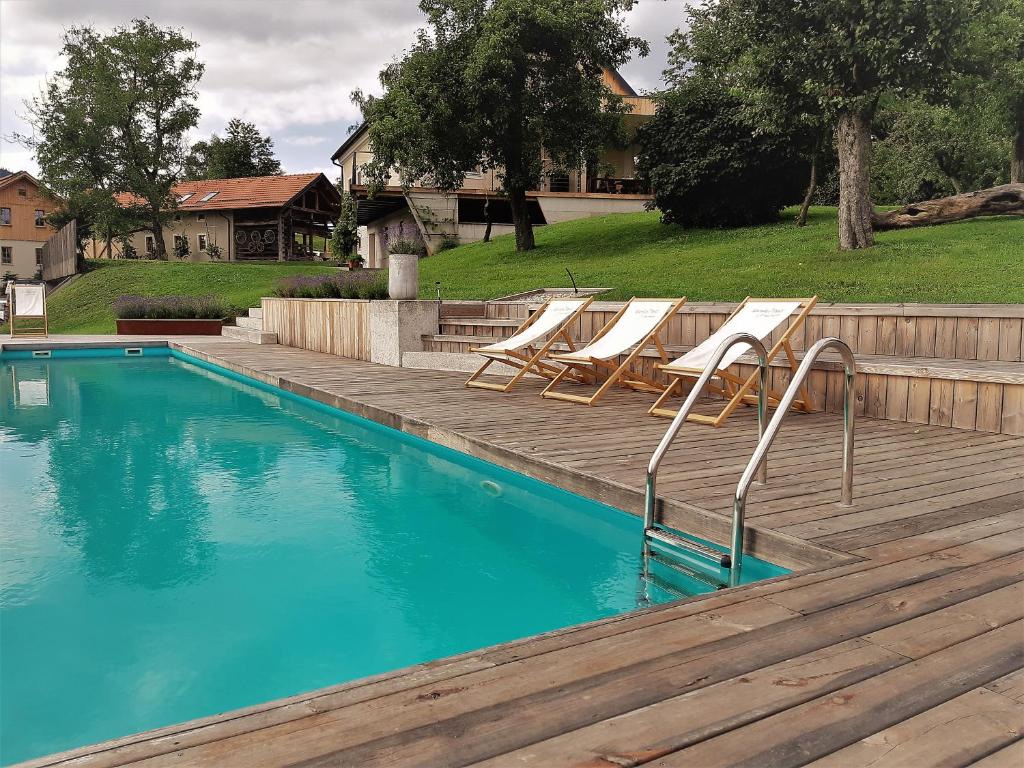 a swimming pool with lounge chairs next to a wooden deck at Lavender Hill, Eko Resort & Wellness in Polzela