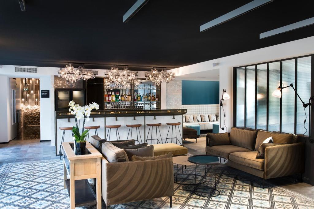 una sala de estar con sofás y un bar en Hôtel Les Deux Girafes en París