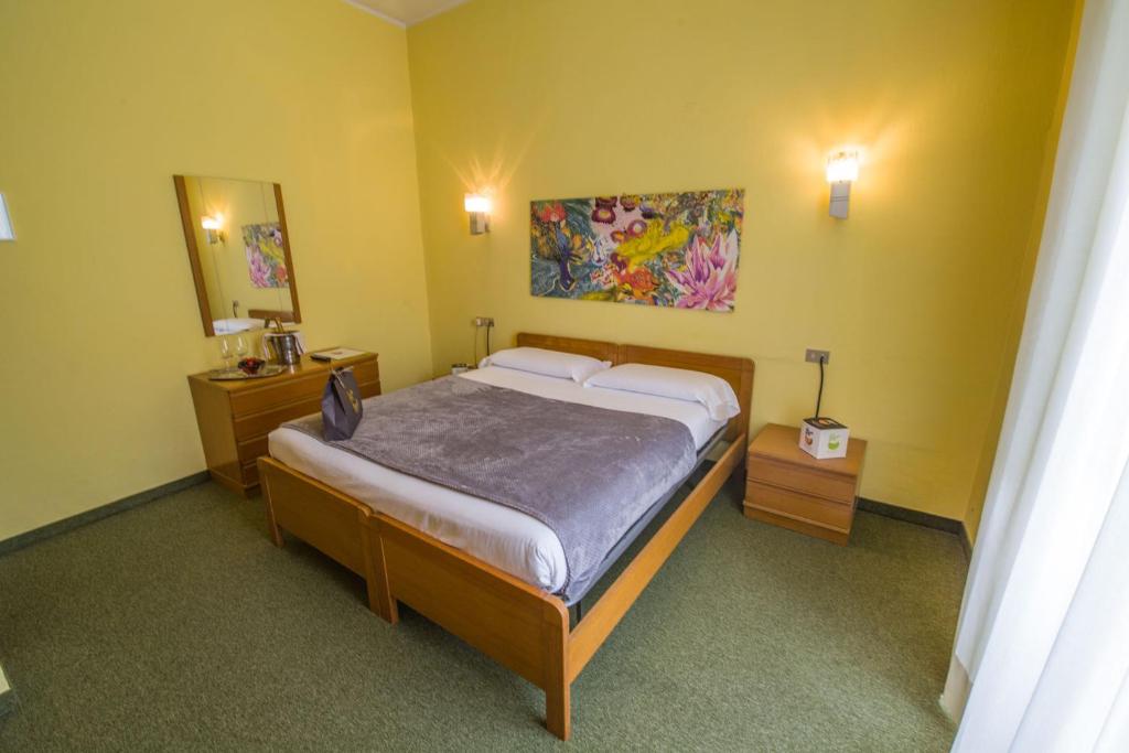 サン・ペッレグリーノ・テルメにあるHotel Bigioのベッドルーム1室(ベッド1台付)が備わります。壁には絵画が飾られています。