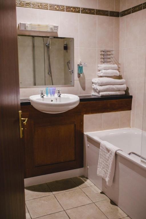 a bathroom with a sink and a tub and a mirror at Inn On The Coast in Portrush