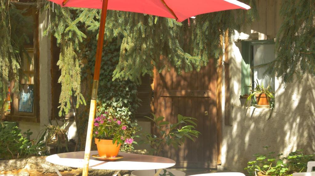 a table with a red umbrella on a patio at La Ferme de Thoudiere in Saint-Étienne-de-Saint-Geoirs