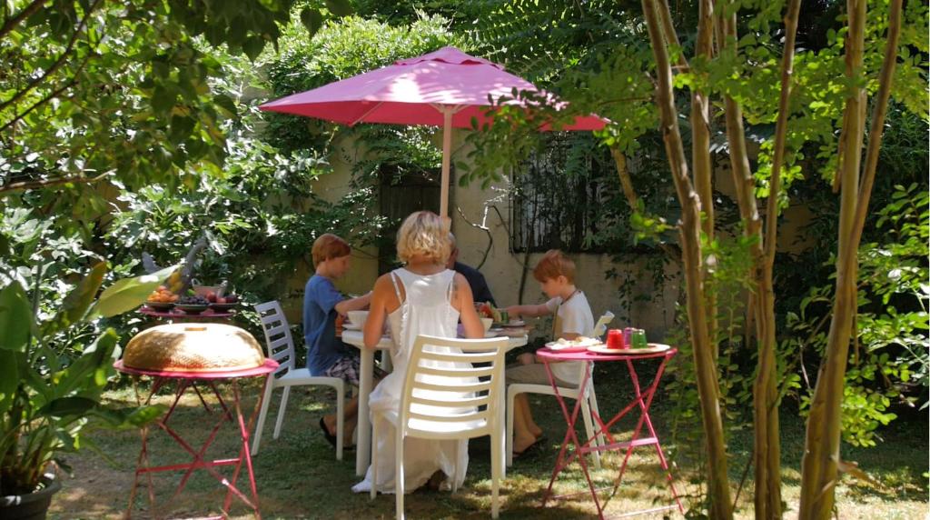 a group of children sitting at tables under an umbrella at La Ferme de Thoudiere in Saint-Étienne-de-Saint-Geoirs