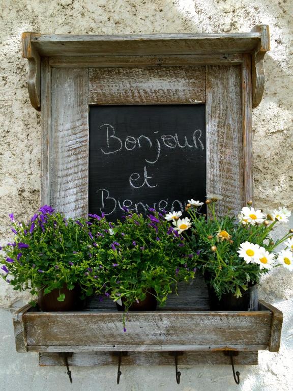 a chalkboard with flowers in a box with a sign at La Ferme de Thoudiere in Saint-Étienne-de-Saint-Geoirs
