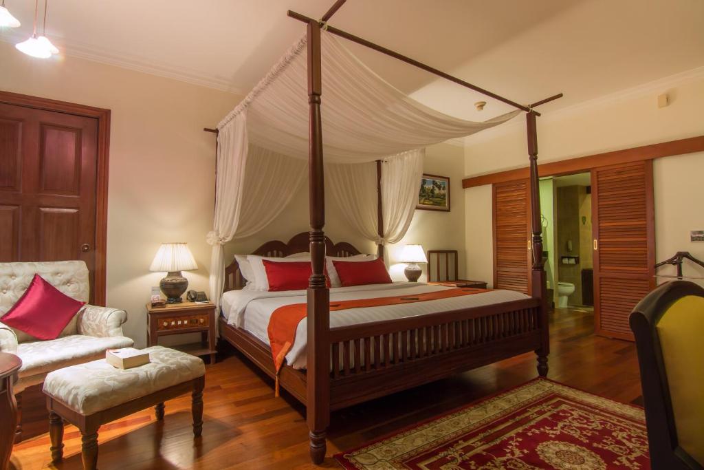 a bedroom with a canopy bed and a couch at Palace Residence & Villa Siem Reap in Siem Reap