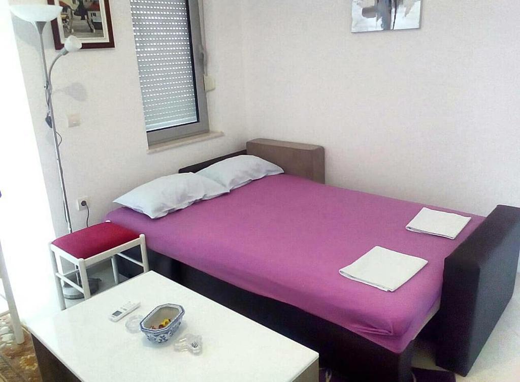 Habitación pequeña con cama morada y mesa. en Topla, en Herceg-Novi