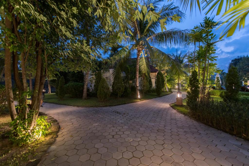 a cobblestone road with palm trees and a building at Palace Residence & Villa Siem Reap in Siem Reap