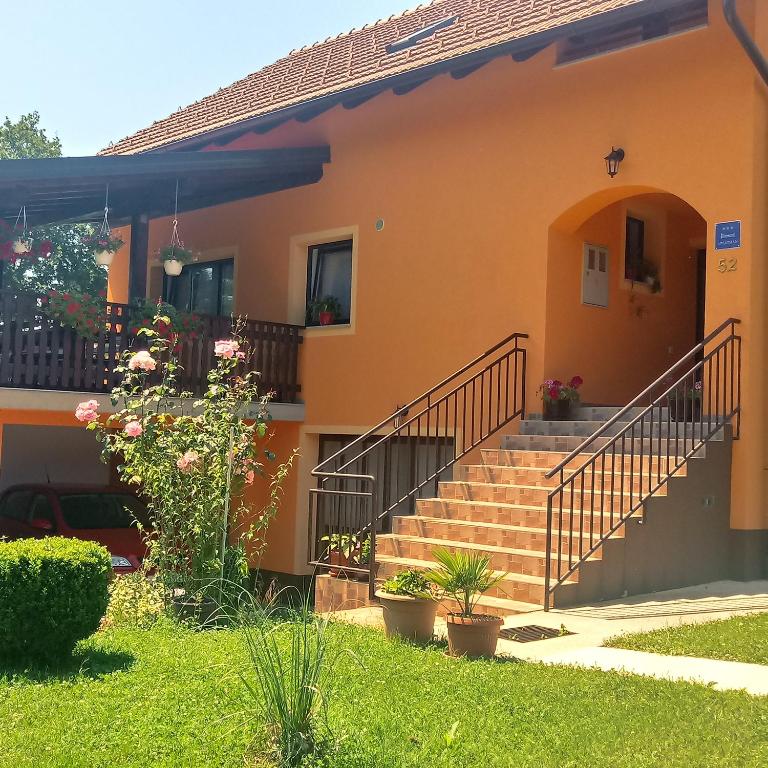 a house with stairs and flowers in the yard at Apartment Petrovic in Slunj