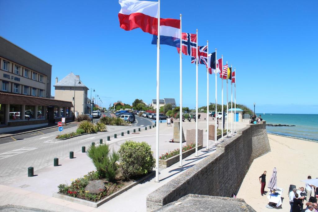 a row of flags on a sidewalk next to the beach at Saint Aubin Logis Hôtel & Restaurant in Saint-Aubin-sur-Mer