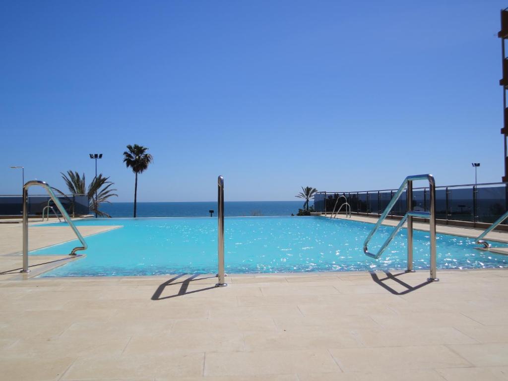 an empty swimming pool with blue water and palm trees at Hotel Angela - Adults Recommended in Fuengirola