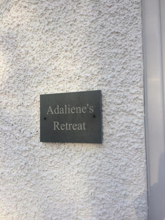 a sign on the side of a white wall at Adalienes Retreat in Portree