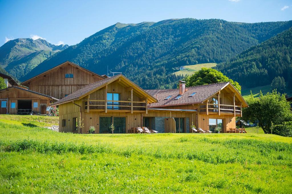 a house in a field with mountains in the background at Mair am Graben Farm * Chalets in Terento