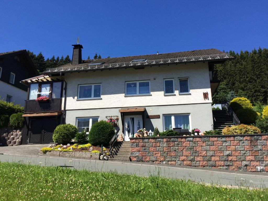 een groot wit huis met een bakstenen muur bij Ferienwohnung Engelmann in Winterberg