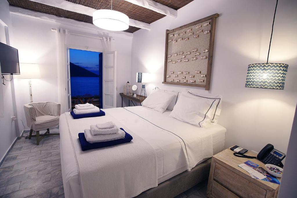 La Playa Boutique Apartments في كاليمنوس: غرفة نوم بسرير ابيض عليها مناشف
