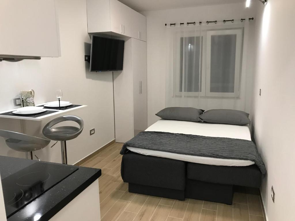 een kleine slaapkamer met een bed en een wastafel bij Apartman studio Ganga in Omiš