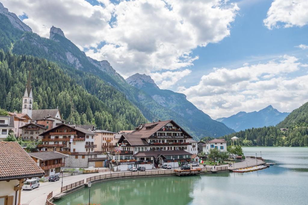 uma cidade ao lado de um lago com montanhas em Sporthotel Europa Sul Lago em Alleghe