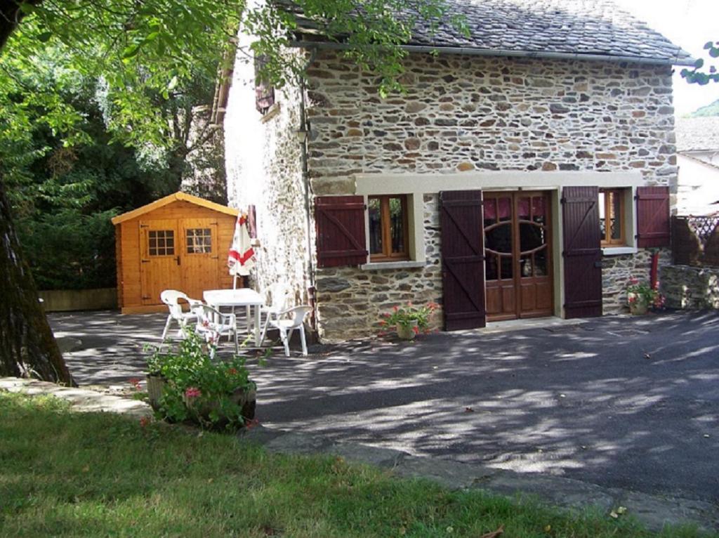 a stone house with a table and chairs in front of it at gite du navech in Camjac