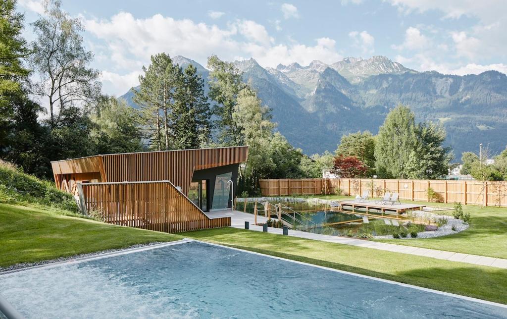 a house with a swimming pool and mountains in the background at Val Blu Sport | Hotel | SPA in Bludenz