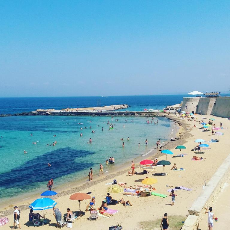 un gruppo di persone su una spiaggia con gli ombrelloni di Elamar Rooms & Apartment a Gallipoli