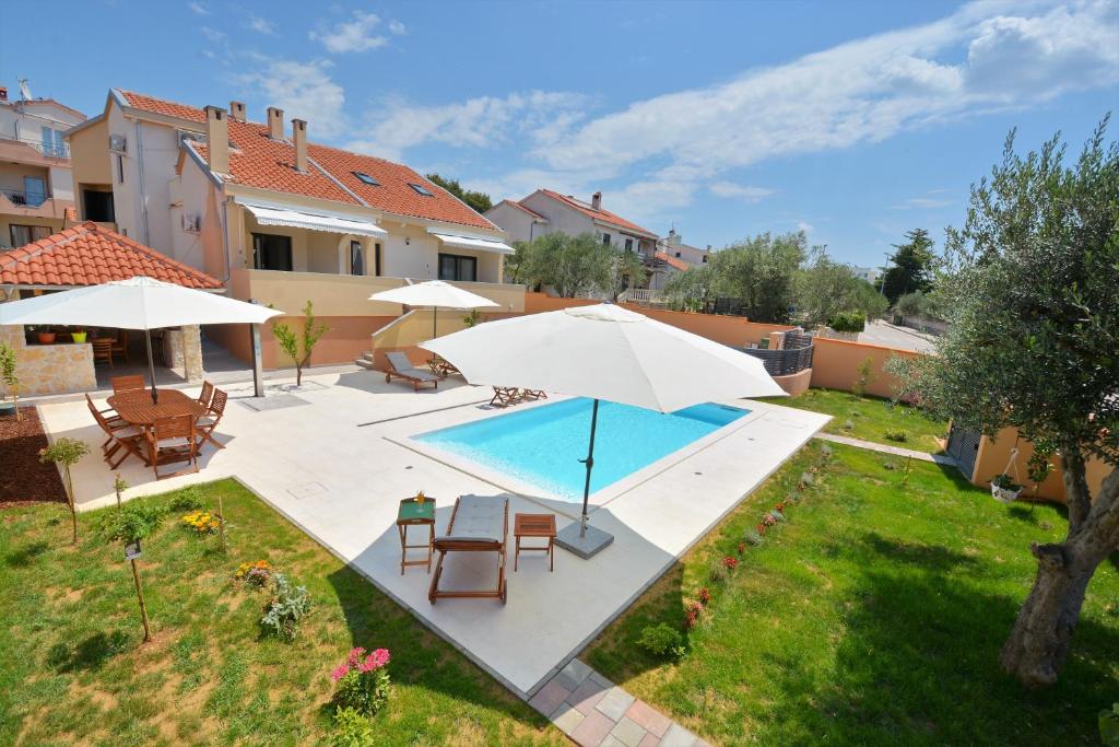 a backyard with a swimming pool and umbrellas at Villa Zupan in Zadar