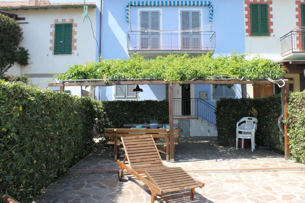 un patio con banco de madera, mesa y sillas en casa azzurra piano terra en Fetovaia