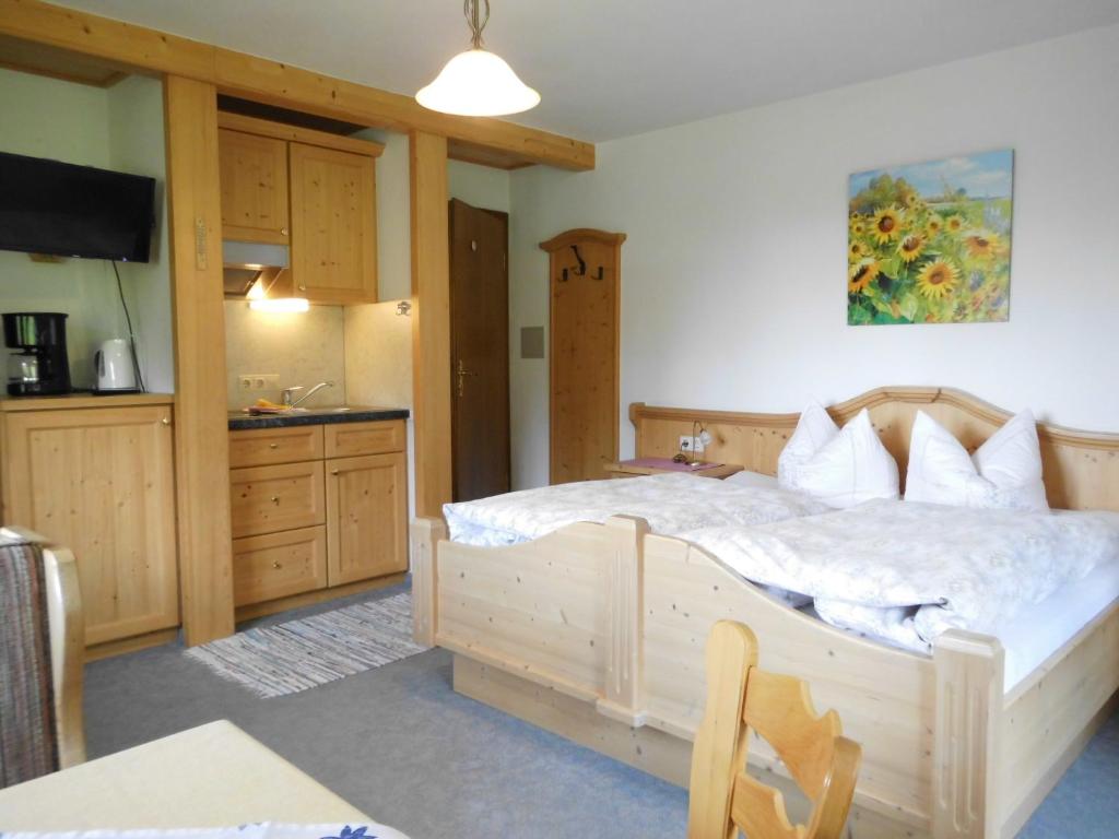 a bedroom with a large bed and a kitchen at Liebertingerhof in Reit im Winkl