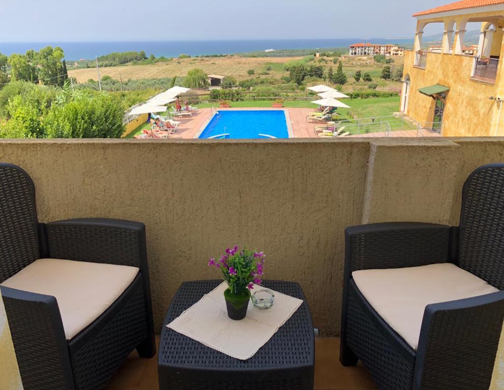 eine Terrasse mit 2 Stühlen und einem Tisch mit Blumen in der Unterkunft Appartamenti Abbaidda in Valledoria