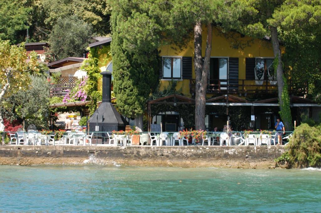 a building with tables and chairs next to a river at Campeggio Ideal Molino in San Felice del Benaco