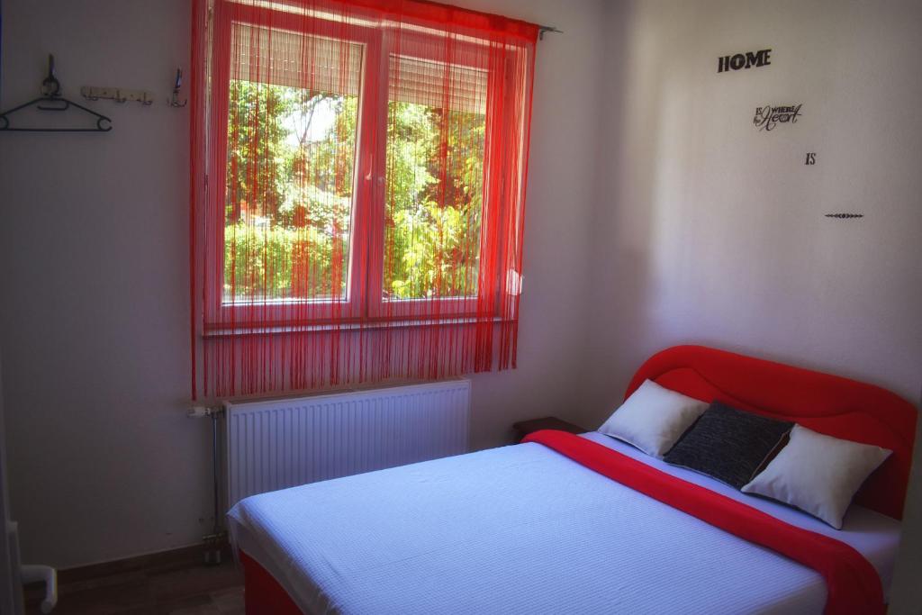 a bed in a bedroom with a red window at Hostel Omega in Banja Luka
