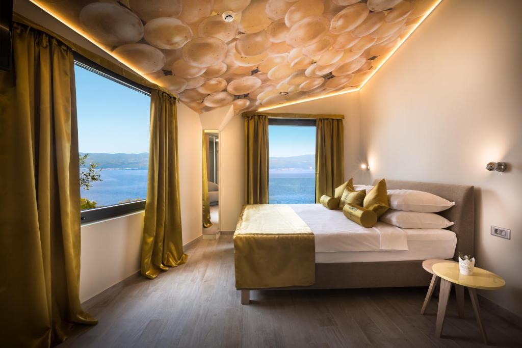 a bedroom with a large bed and large windows at Hotel Vinotel Gospoja in Vrbnik