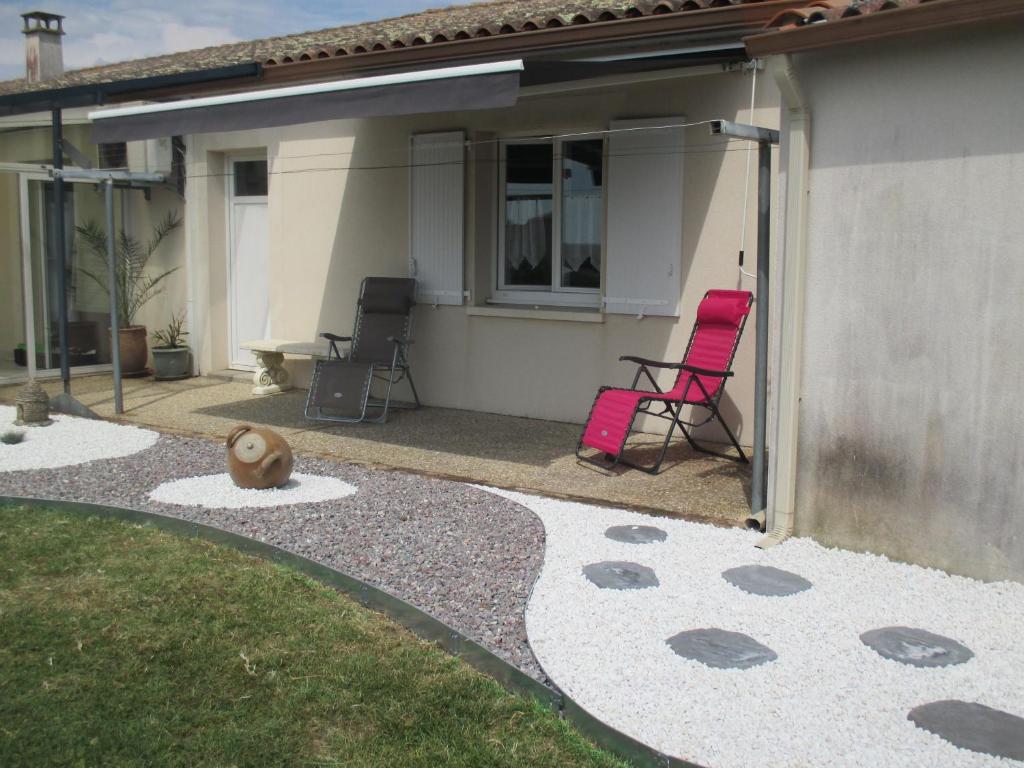 un patio con 2 sillas y una casa en Chambre d'Hôtes Les Ormeaux, en Saint-Georges-des-Côteaux