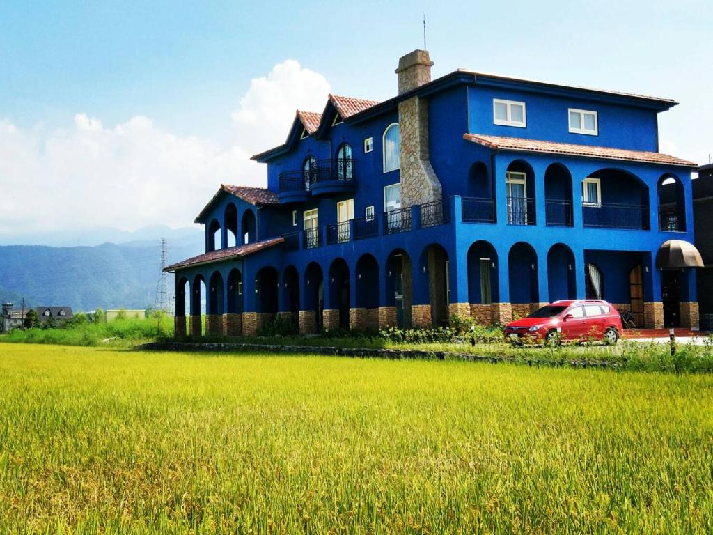 una casa blu con una macchina rossa parcheggiata di fronte di Fly Inn 飛旅宿 a Dongshan