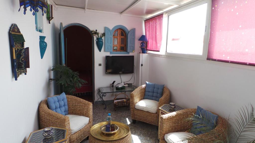 a living room with two chairs and a tv at Riad Dar Zouhour in Rabat