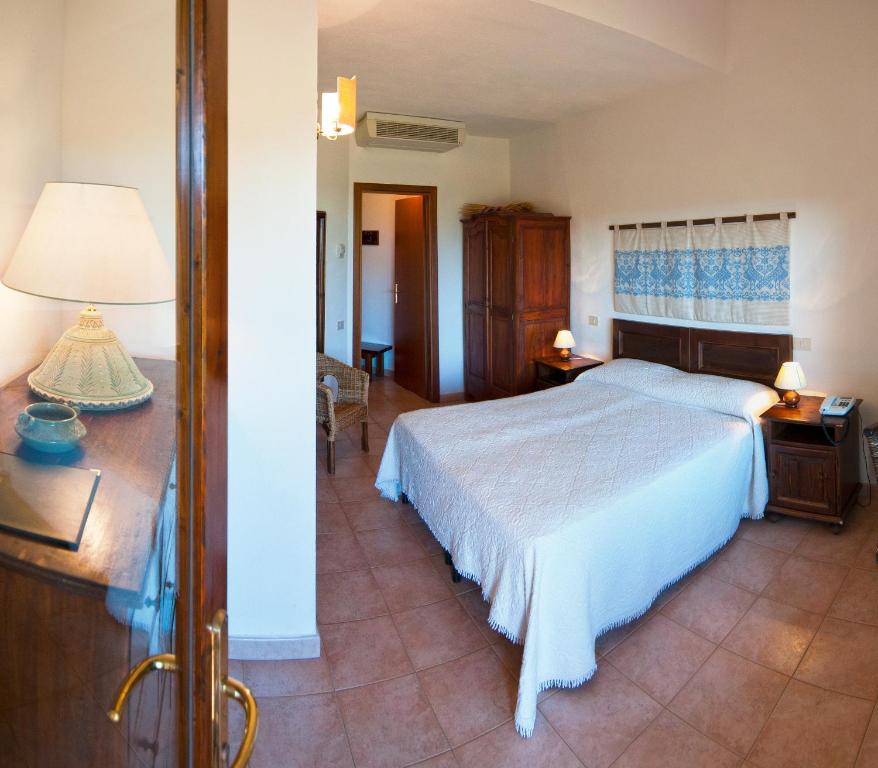 a bedroom with a bed and a table with a lamp at Hotel Spartivento in Chia