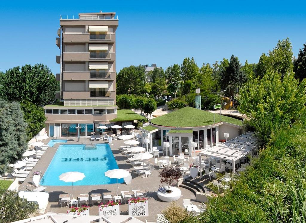 ein Hotel mit einem Pool und Stühlen sowie einem Gebäude in der Unterkunft Hotel Pacific in Cattolica
