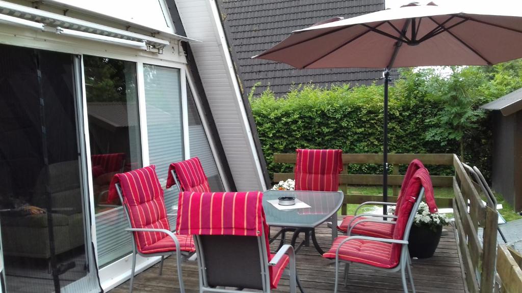 einen Tisch und Stühle mit Sonnenschirm auf einer Terrasse in der Unterkunft Nurdachhaus 128 Ferienpark Fedderwardersiel in Butjadingen
