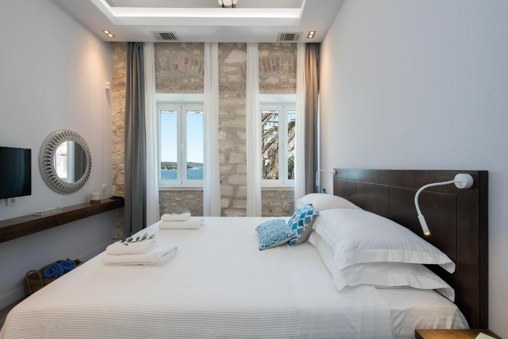 a bedroom with a large white bed with a mirror at Villa Aelia in Kassiopi