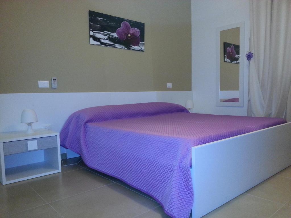 ein Schlafzimmer mit einem lila Bett und einem Tisch in der Unterkunft B&B Il Quadrifoglio in San Vito dei Normanni